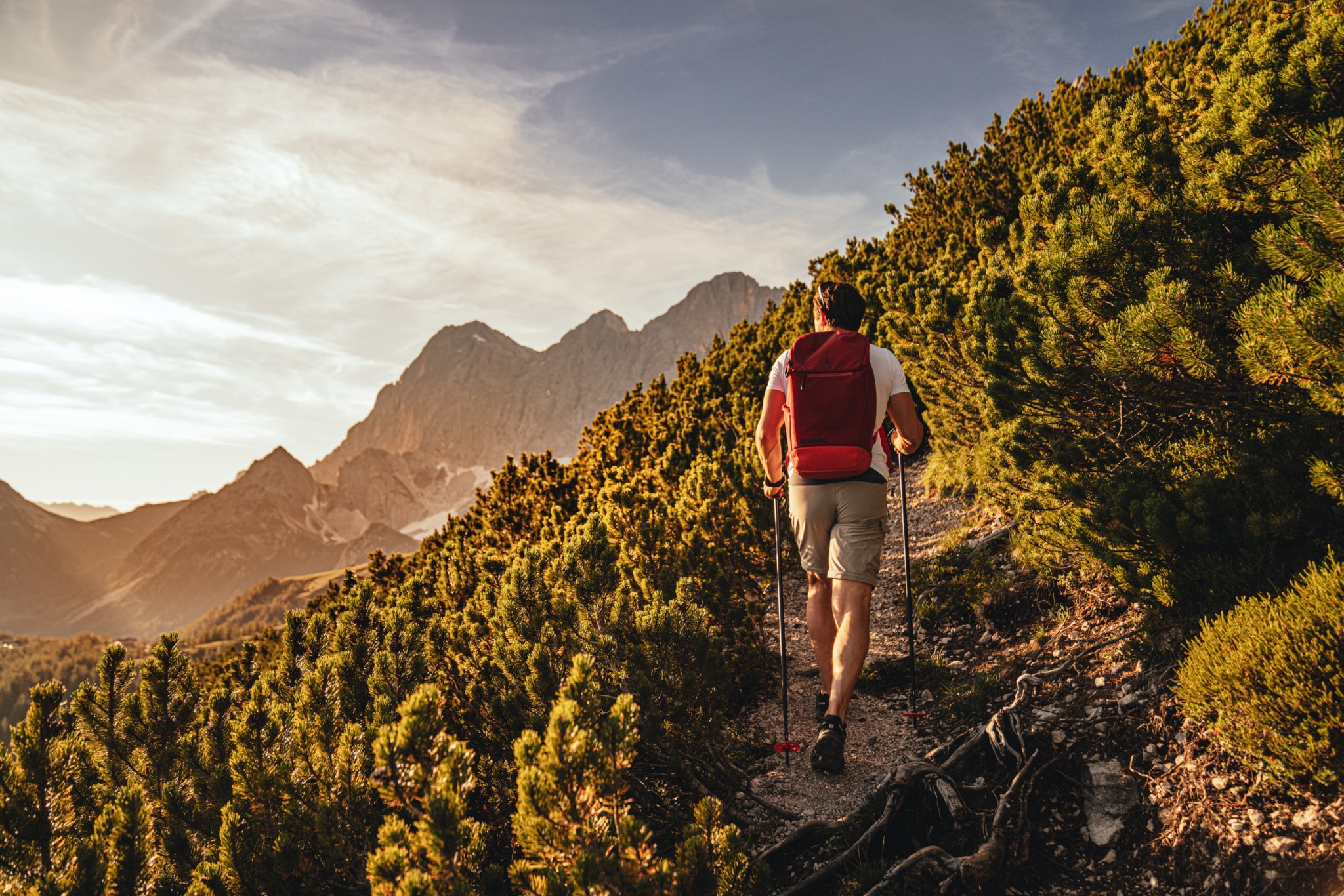Herbstliche Berglandschaft in Schladming mit bunten Wäldern, klarer Fernsicht und einem Wanderer auf einem Panoramaweg – entspannter Herbsturlaub in den Alpen.
